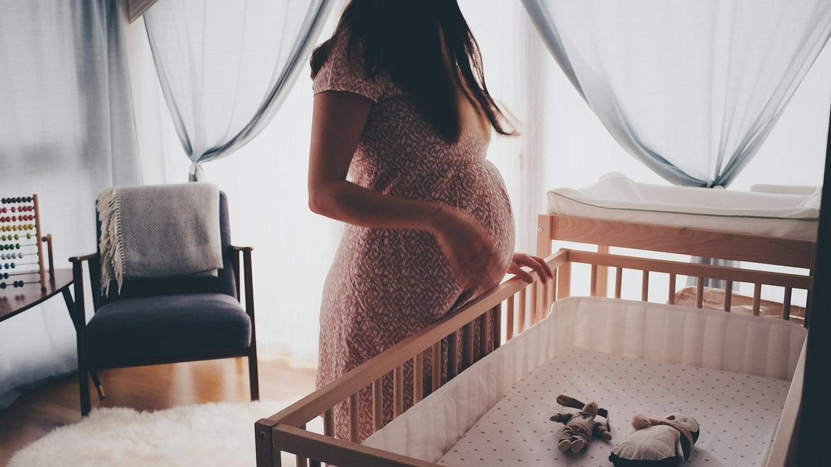 Femme enceinte près d'un berceau dans une chambre de bébé