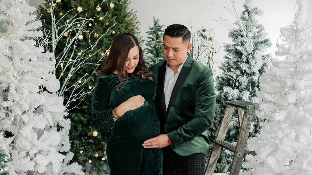 Couple de futurs parents devant un sapin de Noël