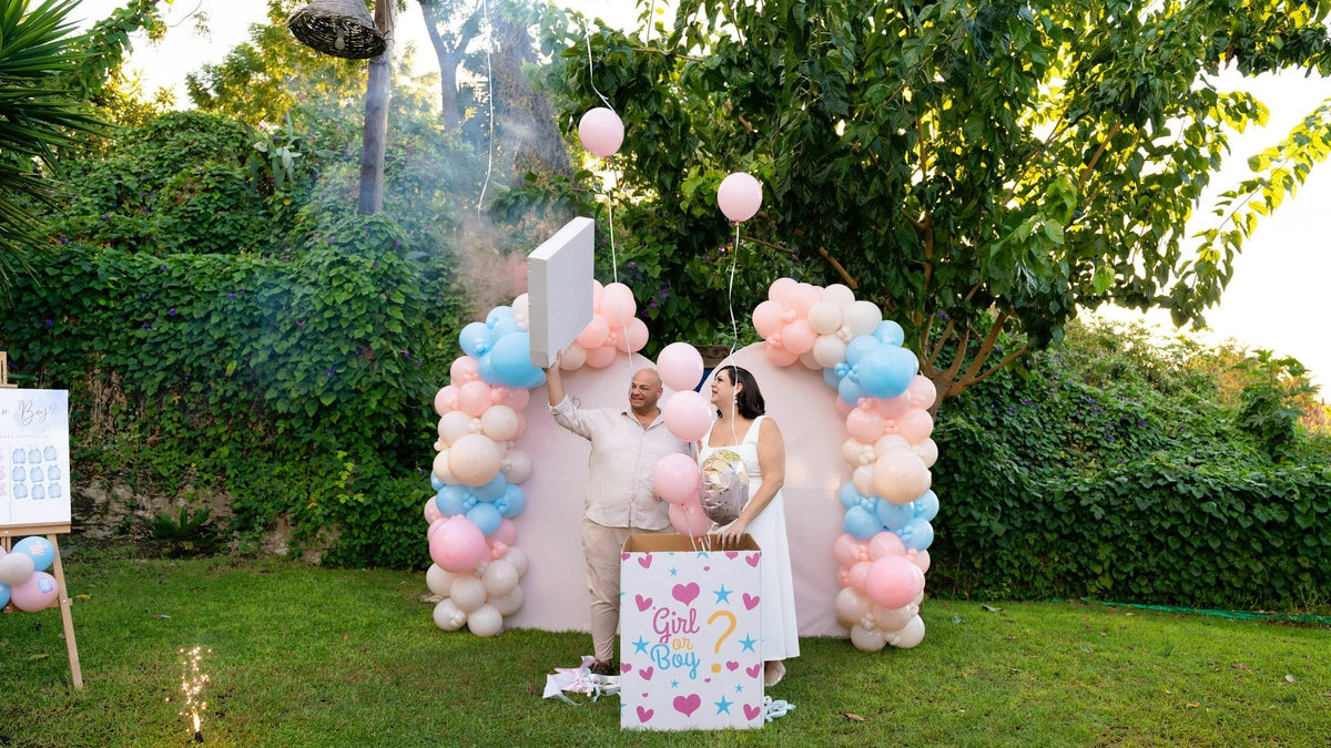 Fête gender reveal avec ballons roses et bleus dans un jardin