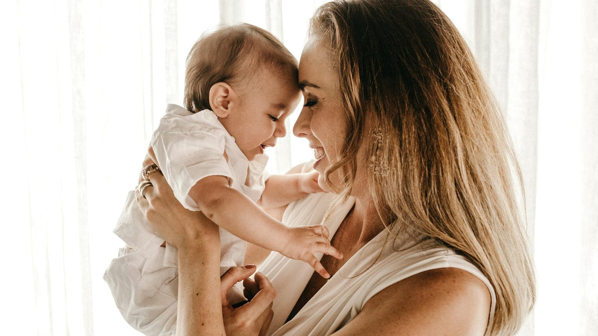 Jeune maman qui soulève son bébé en souriant