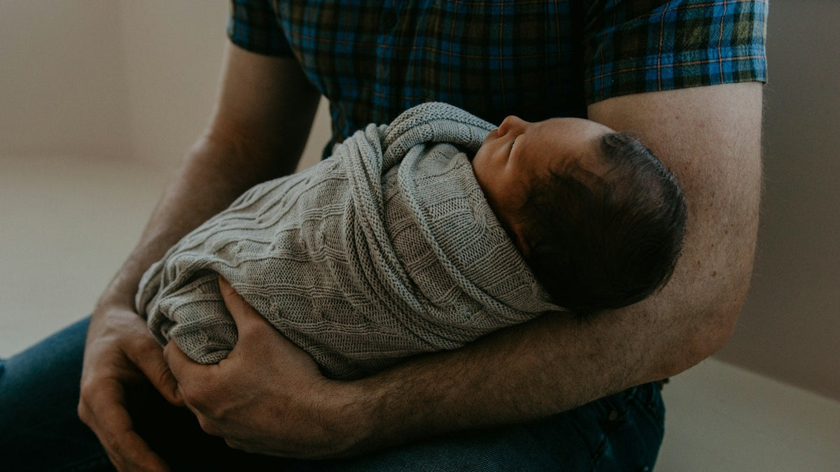 Jeune papa qui tient son nouveau-né dans ses bras