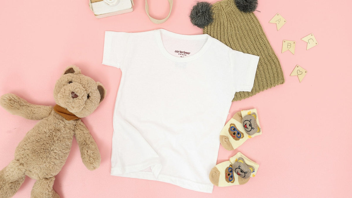 Vêtements de bébé blancs et ours en peluche sur fond rose
