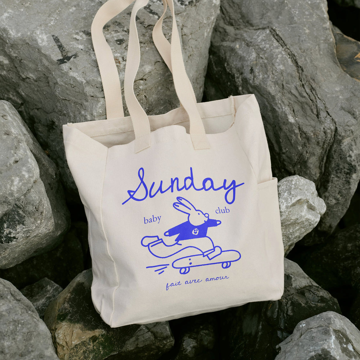 Tote bag Sunday Baby Club au lapin skateur bleu posé sur des rochers – accessoires jeunes parents