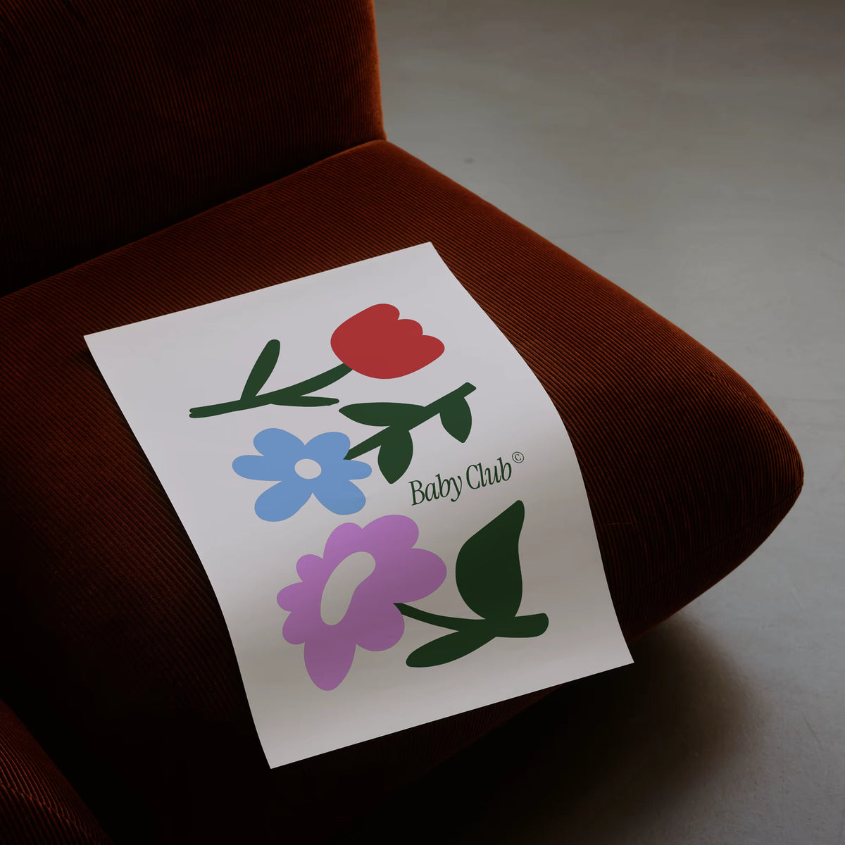 Affiche Baby Club Bouquet illustrée de fleurs rouge, bleue et violette, posée sur un fauteuil – déco chambre bébé